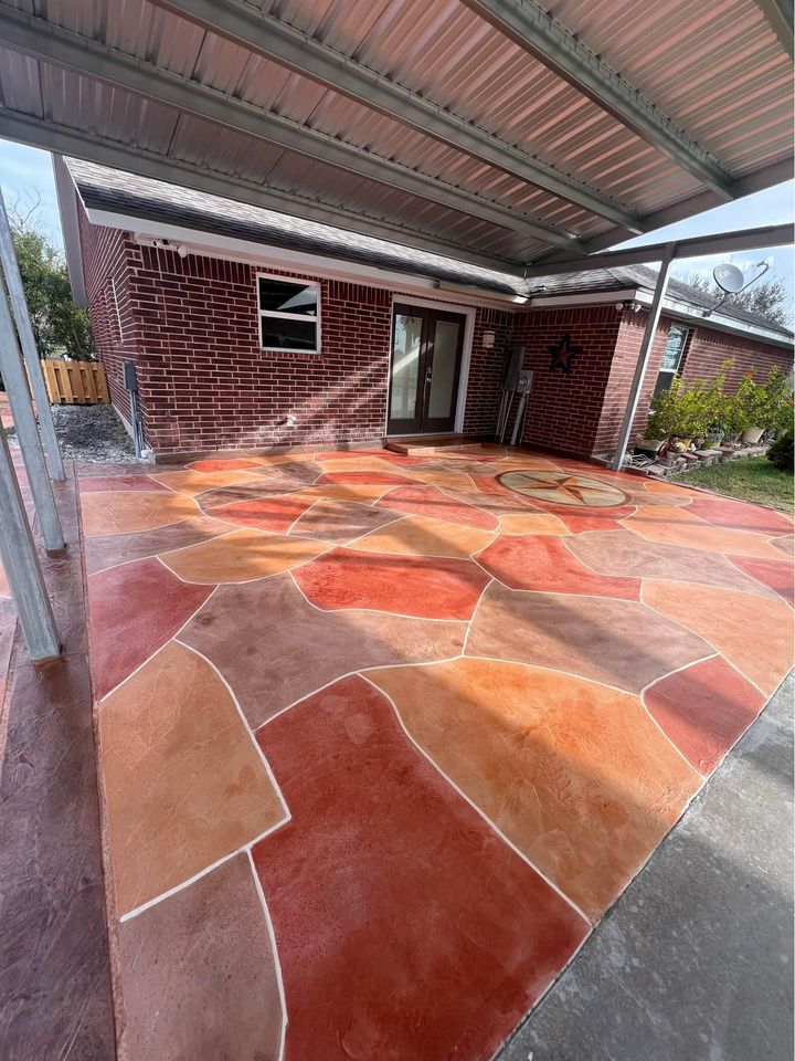 A backyard patio with a vibrant, multi-colored concrete floor featuring an abstract geometric design. The patio is covered with a metal pergola and adjoins a brick house with a sliding glass door. For those inspired by this look, Scottsdale concrete contractor offers free concrete service quotes for your dream patio transformation.